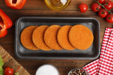 Photo of Uncooked breaded cutlets on wooden table, flat lay. Freshly frozen semi-finished product