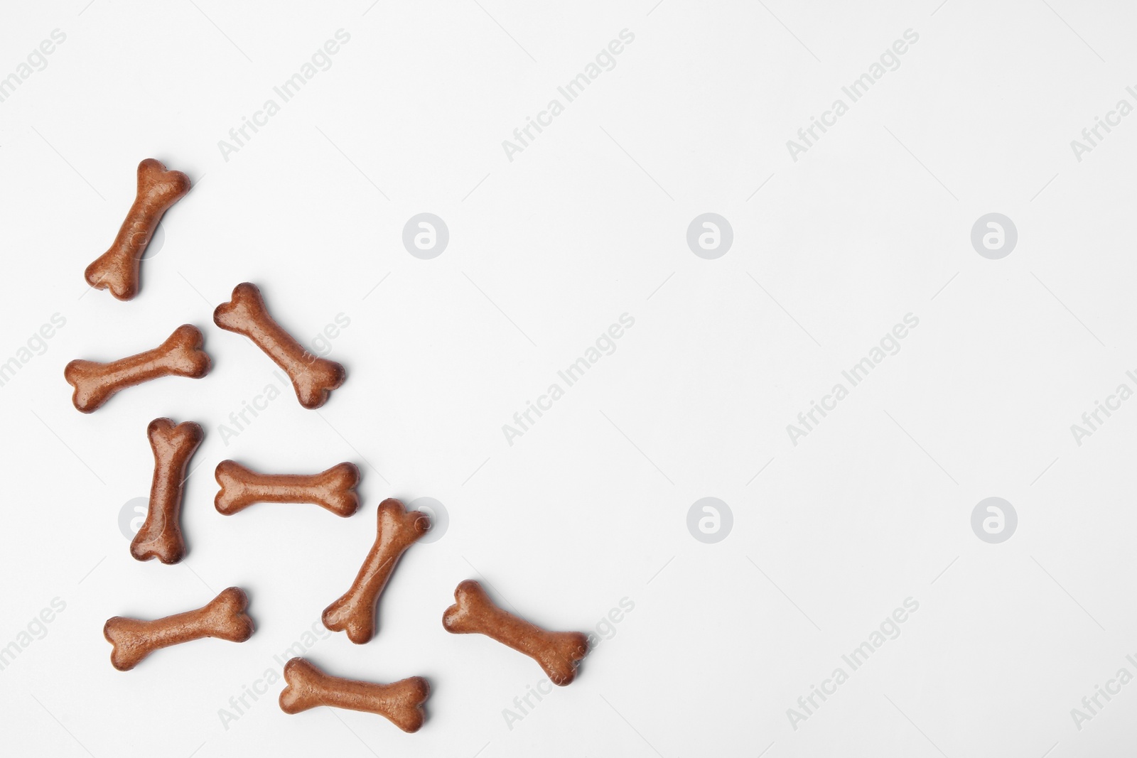 Photo of Bone shaped dog cookies on white background, flat lay. Space for text