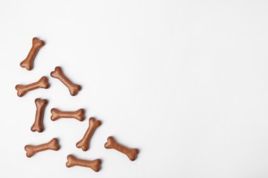 Photo of Bone shaped dog cookies on white background, flat lay. Space for text