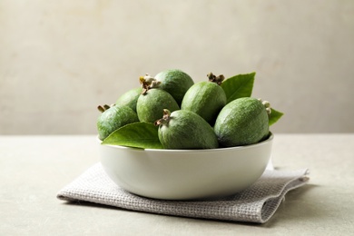 Delicious fresh feijoas in bowl on light grey table