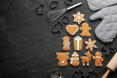 Photo of Kitchen utensils near Christmas tree shape made of delicious gingerbread cookies on black table, flat lay. Space for text