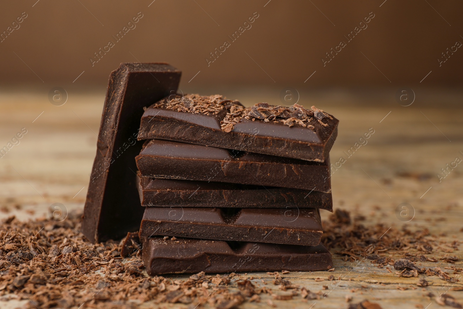 Photo of Pieces and shavings of tasty chocolate on wooden table, closeup