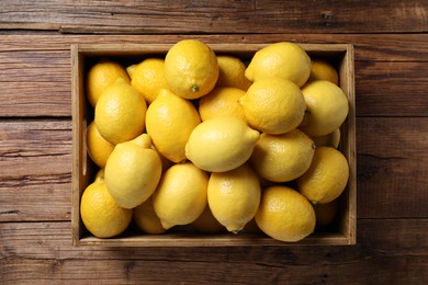 Fresh lemons in crate on wooden table, top view