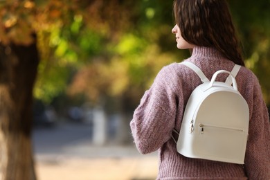 Young woman with stylish white backpack in park, back view. Space for text
