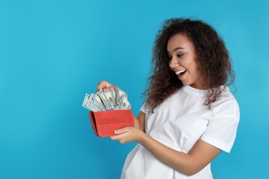 Photo of African-American woman with money in wallet on color background