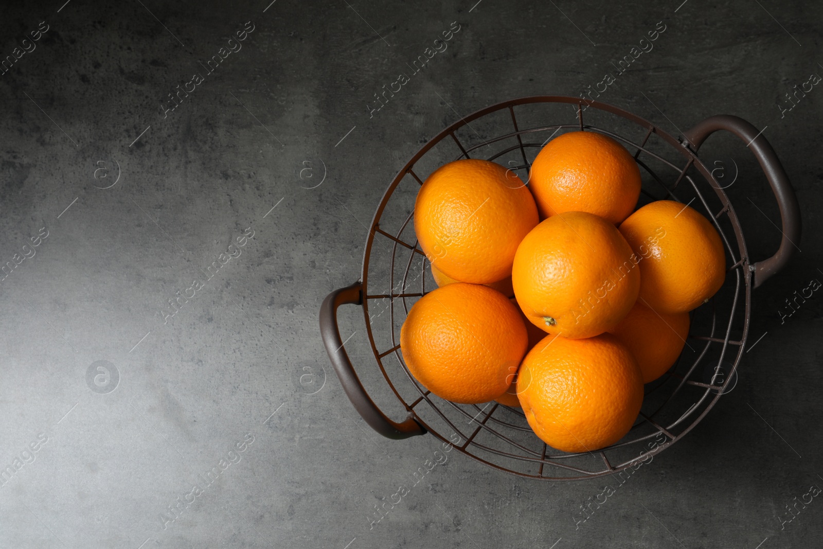 Photo of Basket with ripe oranges on grey background, top view. Space for text