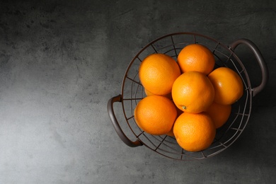 Basket with ripe oranges on grey background, top view. Space for text