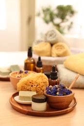 Photo of Dry flowers, loofah, soap bar, bottle of essential oil and jar with cream on wooden table indoors. Spa time