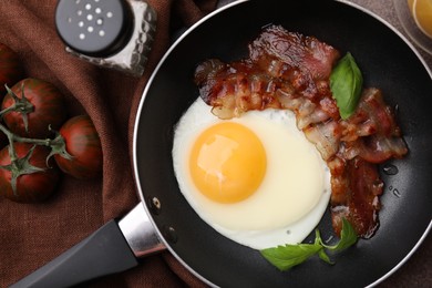 Fried egg, bacon, basil and tomatoes on table, top view