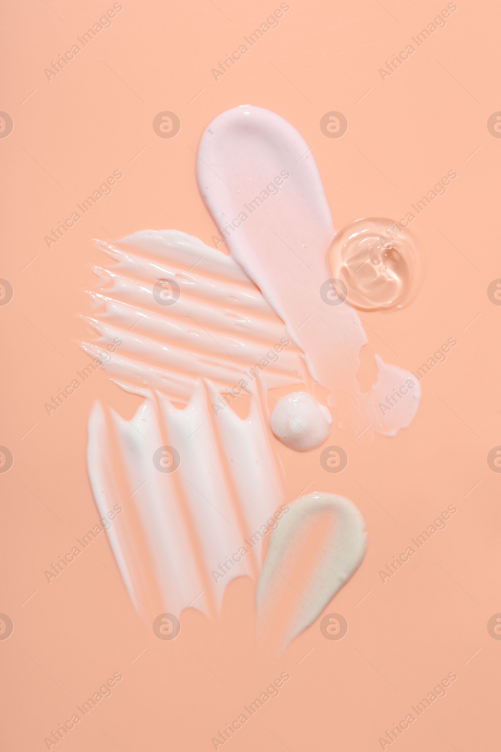 Photo of Samples of face cream on coral background, top view