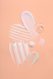 Photo of Samples of face cream on coral background, top view