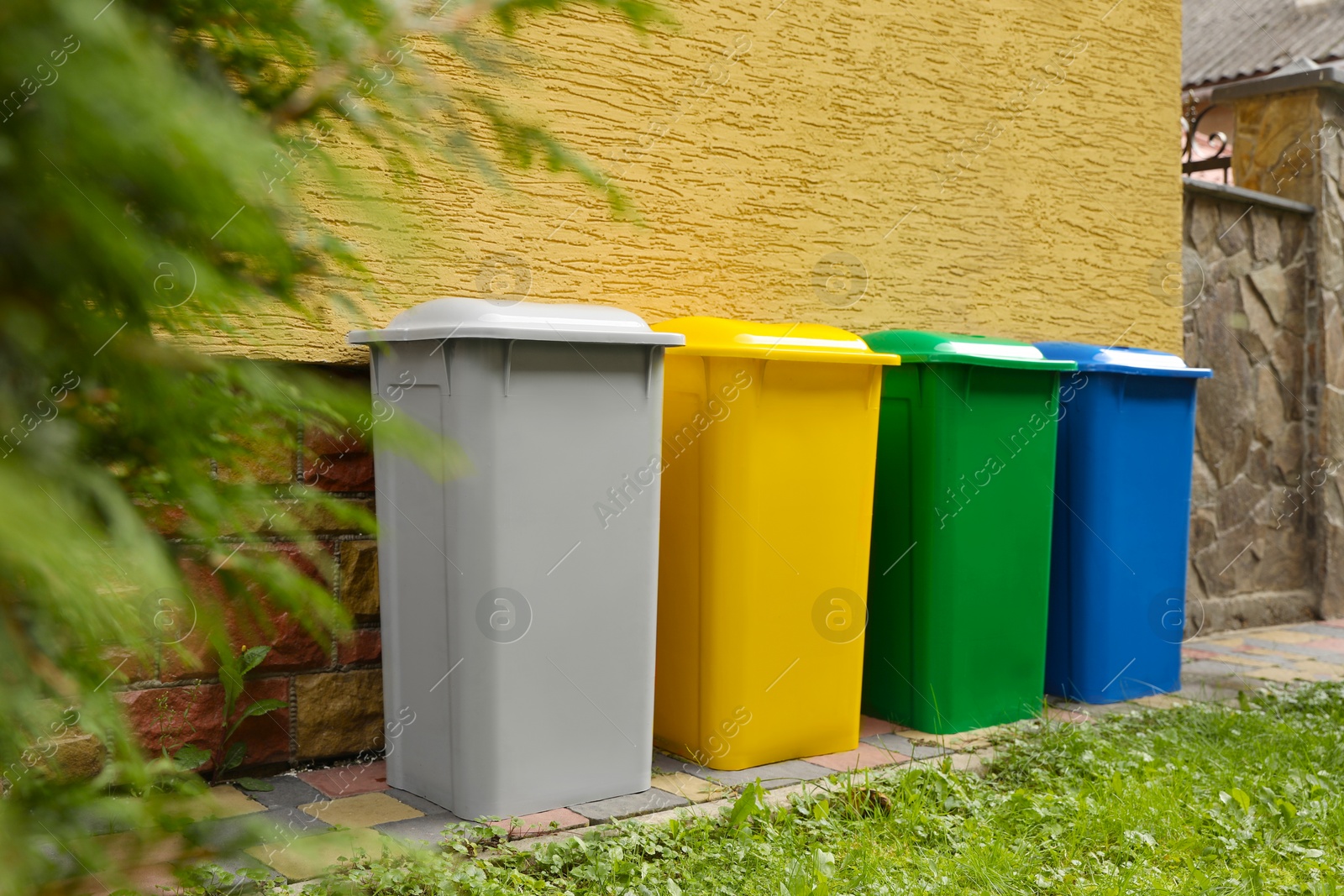 Photo of Many colorful recycling bins near yellow wall outdoors