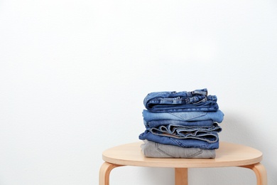 Photo of Stack of different jeans on table against white background. Space for text