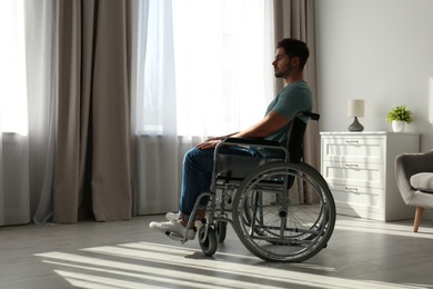 Photo of Young man sitting in wheelchair near window indoors