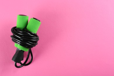 Skipping rope on pink background, top view. Space for text