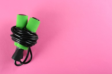 Photo of Skipping rope on pink background, top view. Space for text