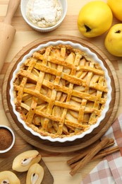 Photo of Tasty homemade quince pie and ingredients on wooden table, flat lay