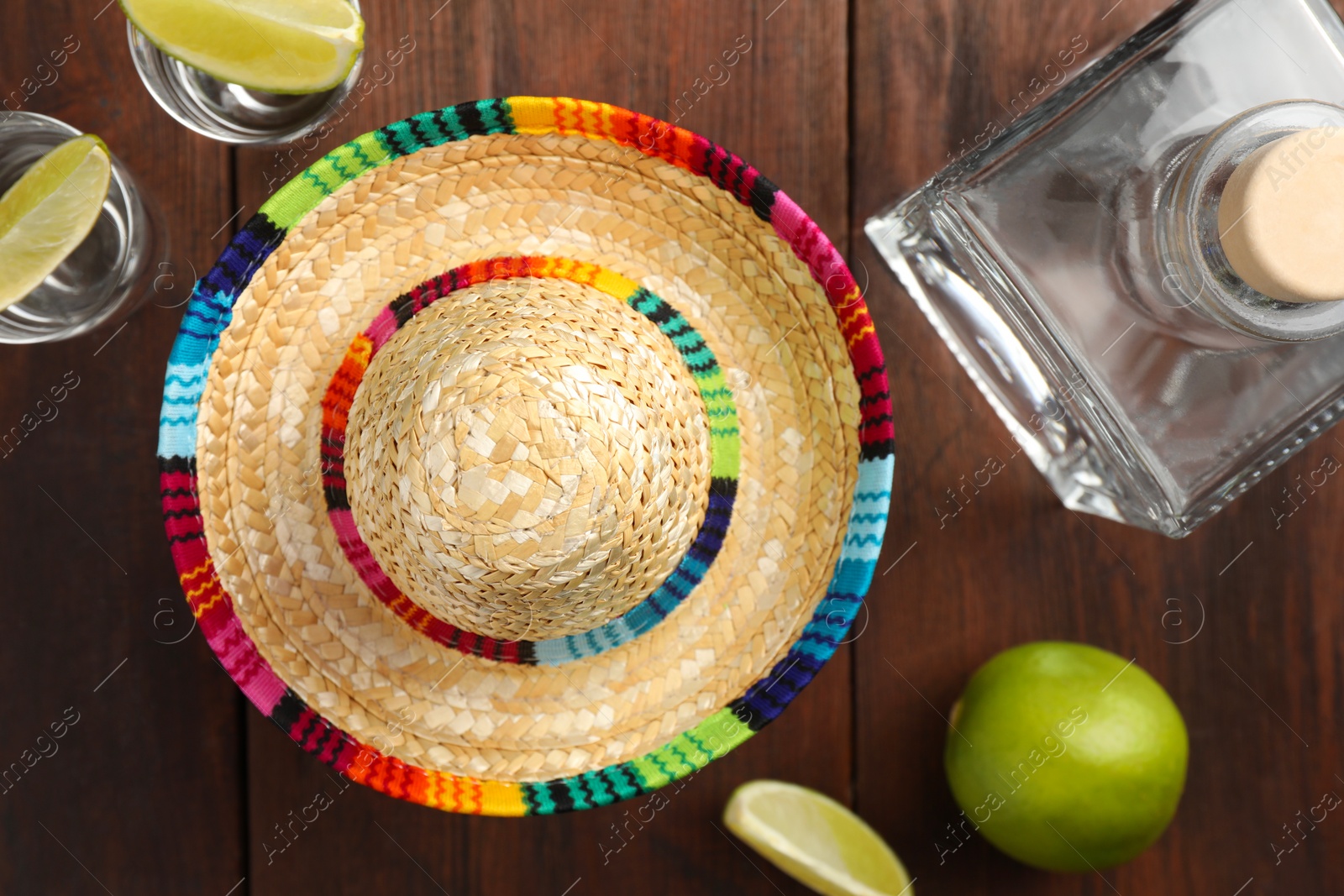 Photo of Mexican sombrero hat, tequila and lime on wooden table, flat lay