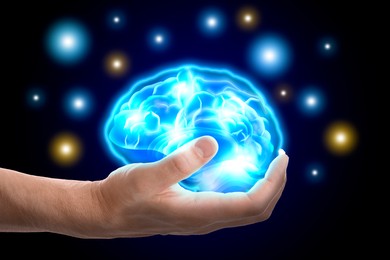 Man holding illustration of brain in hand on black background, closeup
