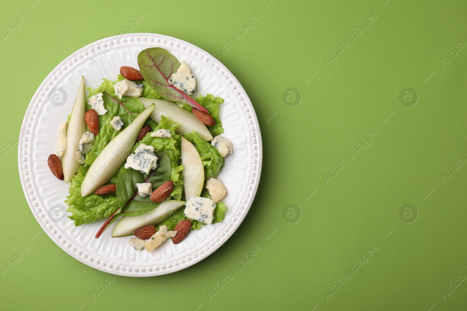 Photo of Delicious pear salad on green background, top view. Space for text