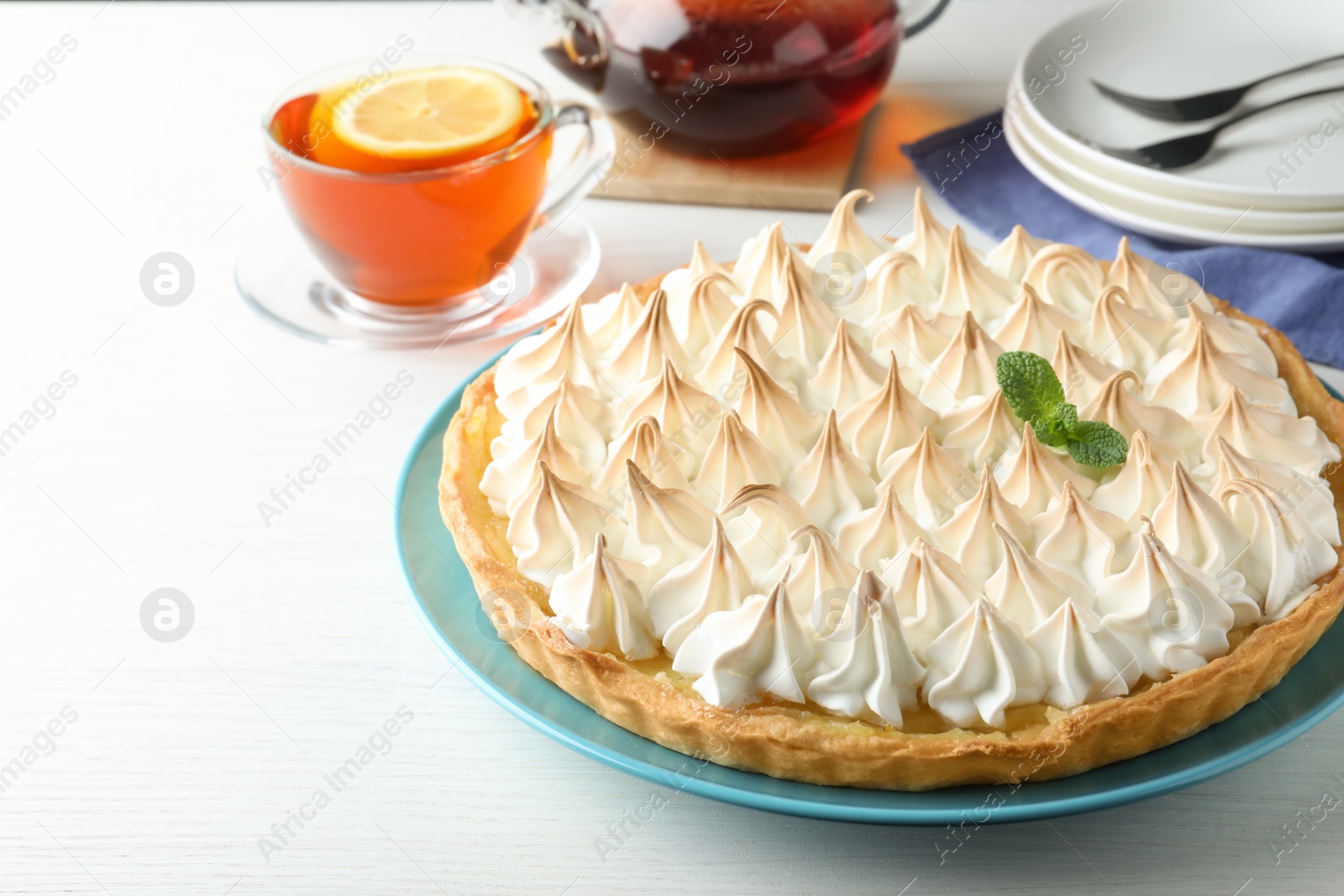Photo of Delicious lemon meringue pie decorated with mint on  white table, space for text