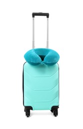 Photo of Soft travel pillow on turquoise suitcase isolated on white