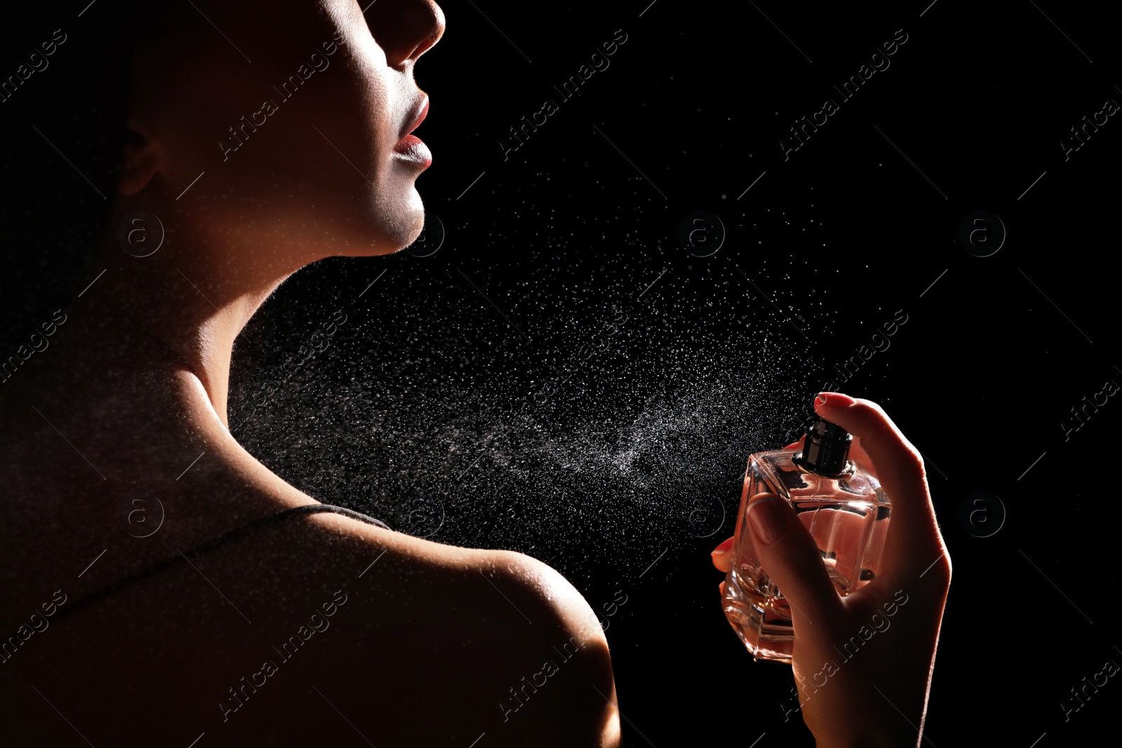 Photo of Woman spraying luxury perfume on black background, closeup