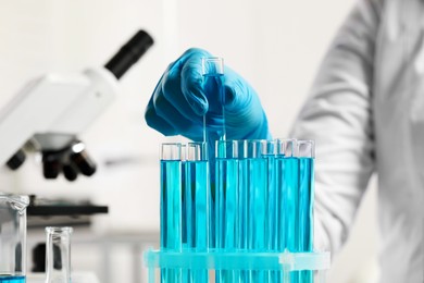 Photo of Scientist taking test tube with light blue liquid in laboratory, closeup