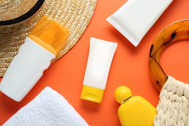 Photo of Suntan products, straw hat and bag on orange background, flat lay