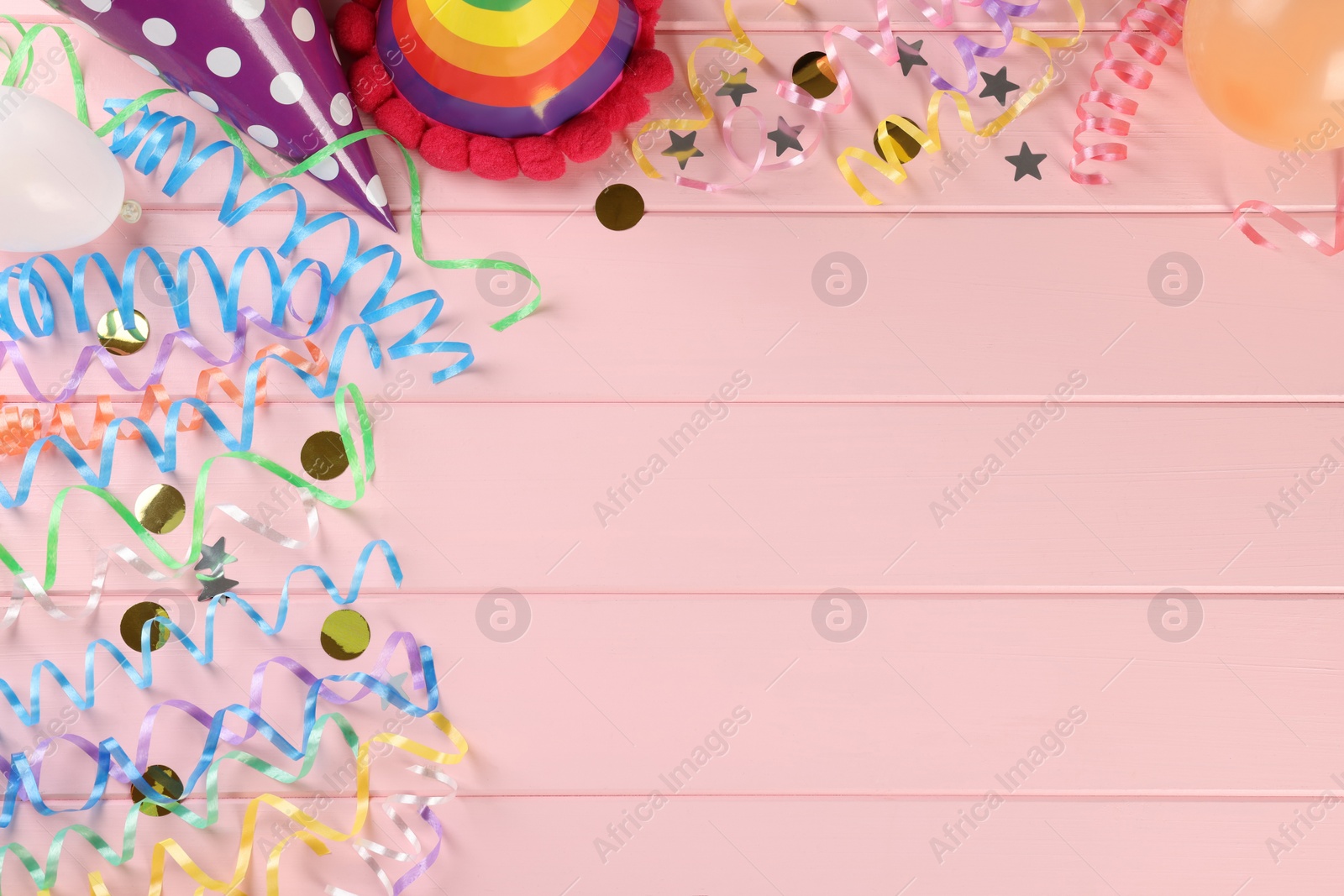 Photo of Flat lay composition with colorful serpentine streamers and confetti on pink wooden table, space for text