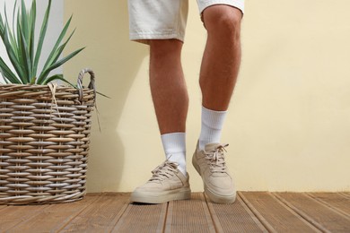 Photo of Man wearing stylish sneakers near beige wall, closeup