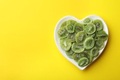 Photo of Plate of dried kiwi on color background, top view with space for text. Tasty and healthy fruit