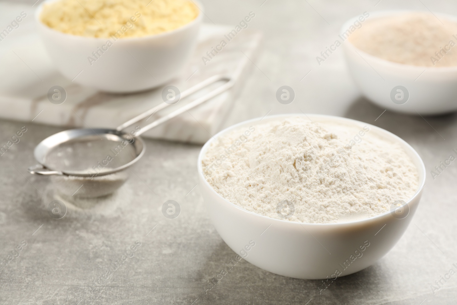 Photo of Bowl of flour on light grey table. Space for text