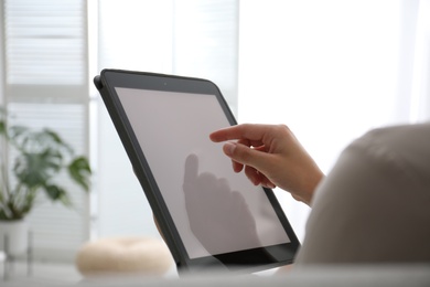 Photo of Woman using modern tablet at home, closeup. Space for design