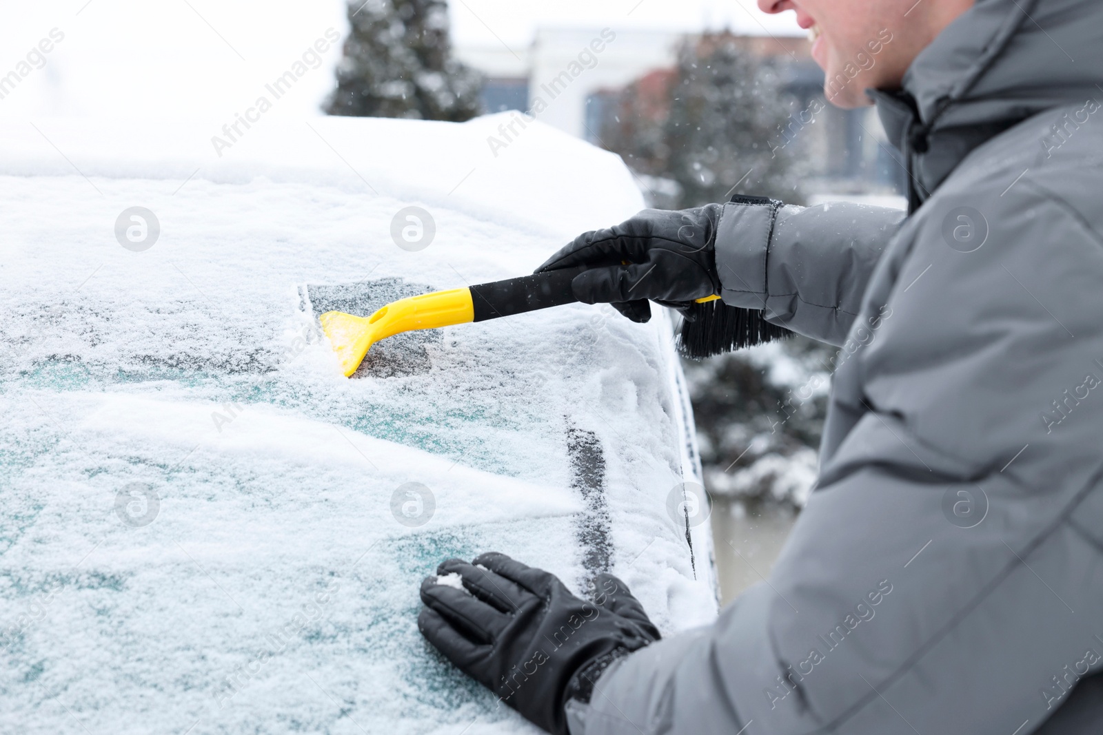 Photo of Man cleaning snow from car windshield outdoors, closeup