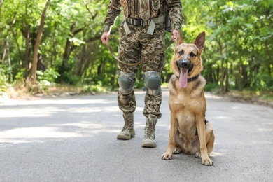 Photo of Man in military uniform with German shepherd dog outdoors