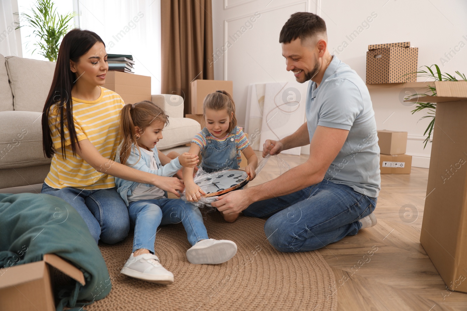 Photo of Happy family unpacking clock at their new house on moving day