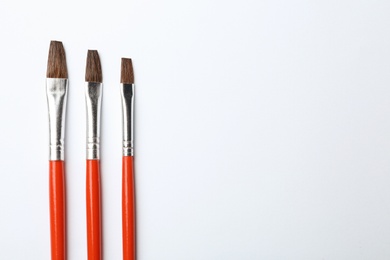 Different paint brushes on white background, top view. Space for text