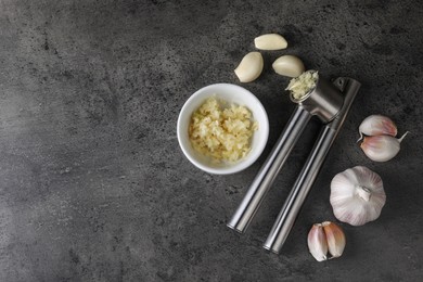 Photo of Garlic press, cloves and mince on grey table, flat lay. Space for text