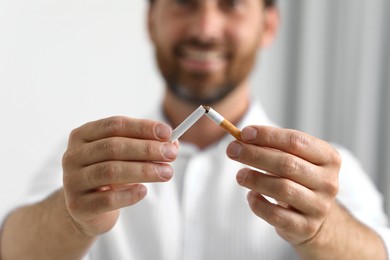 Photo of Stop smoking concept. Man breaking cigarette on light background, selective focus