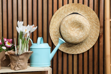 Composition with watering can and flowers on crate at wooden wall. Spring gardening