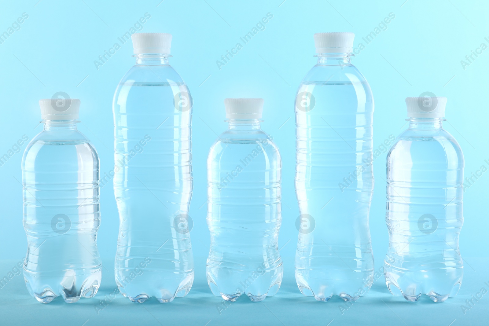 Photo of Row of different plastic bottles with water on color background