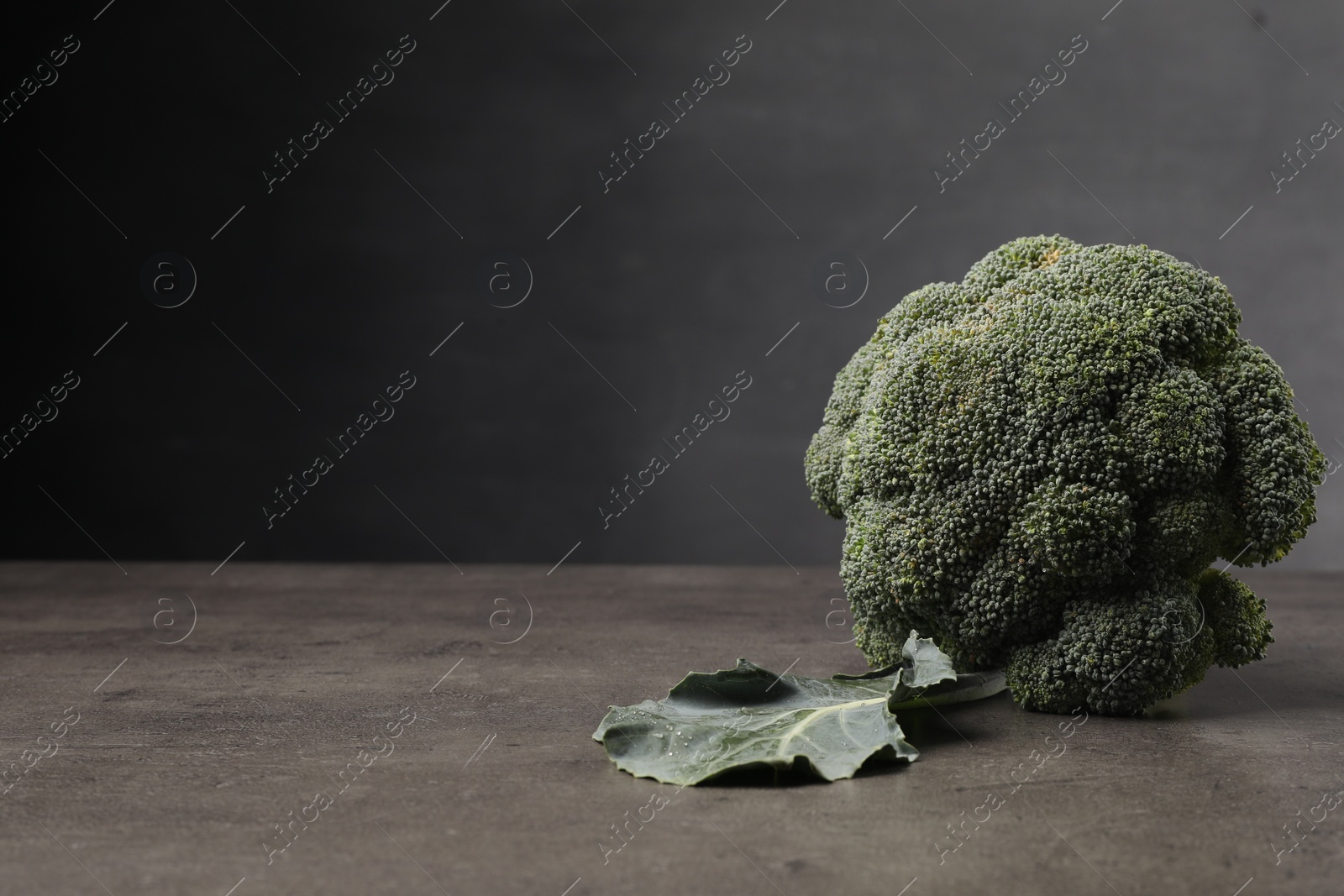 Photo of Fresh raw broccoli on grey table, closeup. Space for text