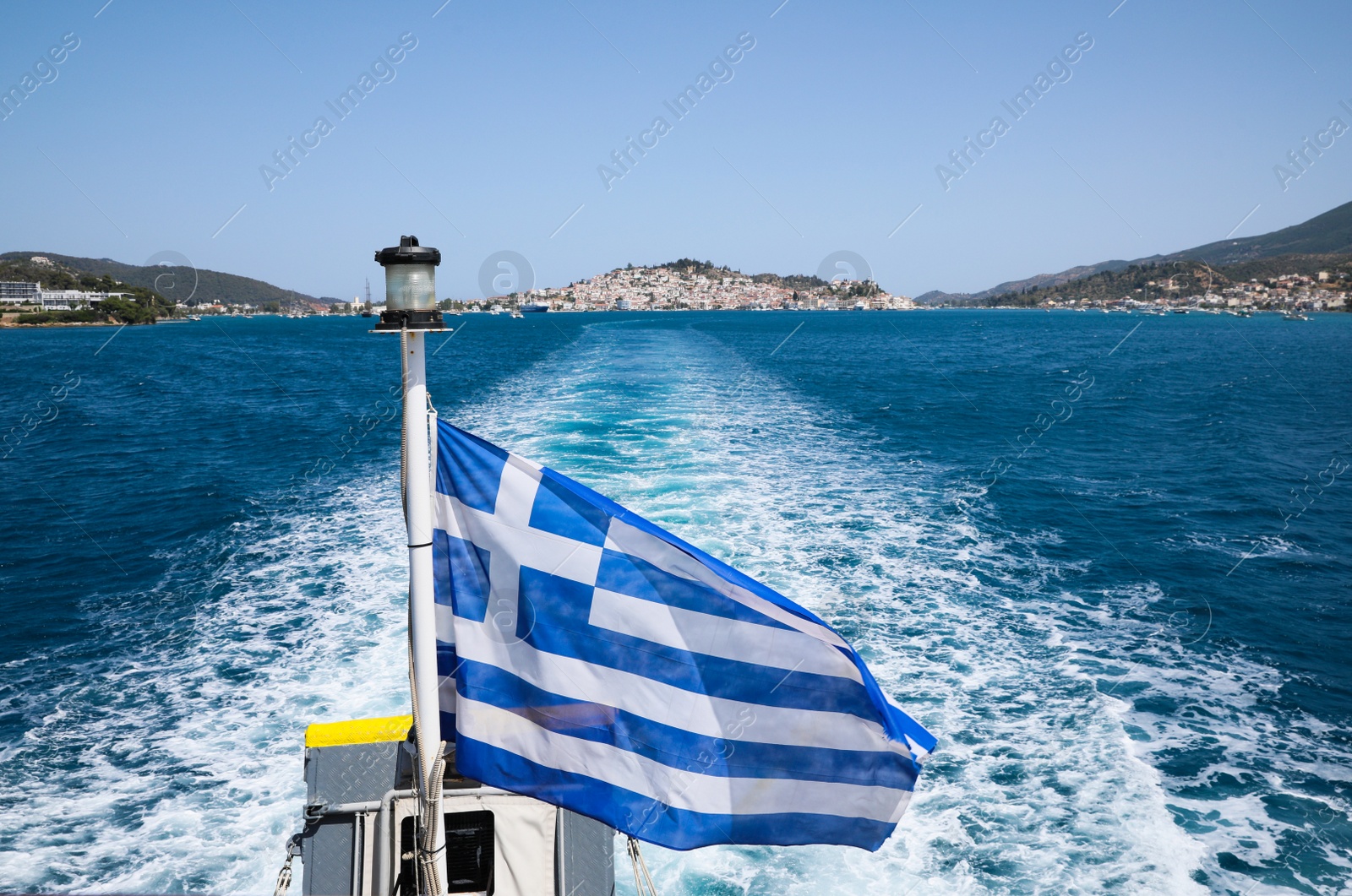 Photo of POROS, GREECE - MAY 28, 2022: Beautiful boat with flag of Greece in sea on sunny day