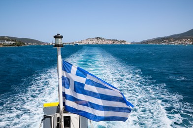 POROS, GREECE - MAY 28, 2022: Beautiful boat with flag of Greece in sea on sunny day