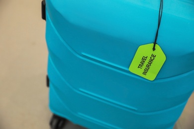 Photo of Suitcase with TRAVEL INSURANCE label indoors, closeup
