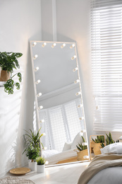 Photo of Stylish mirror with light bulbs in modern bedroom. Interior design
