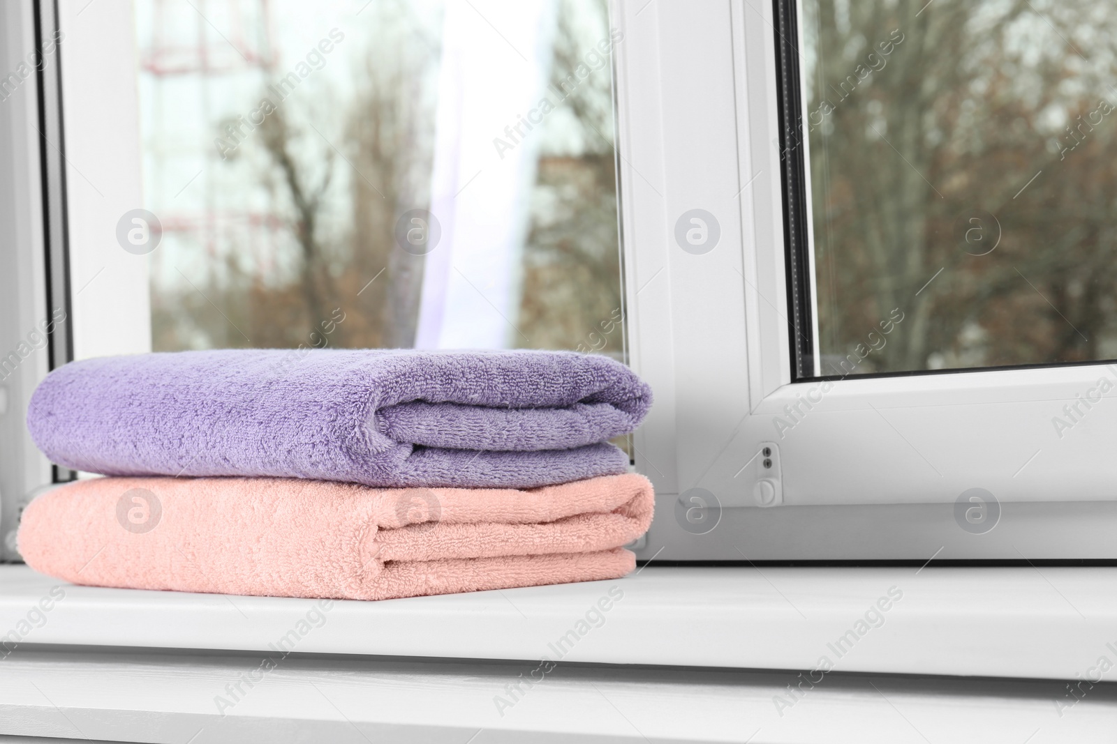 Photo of Folded clean towels on window sill. Space for text