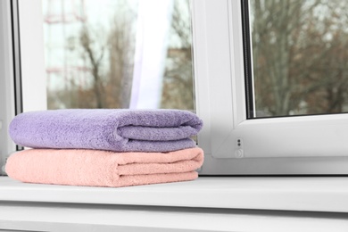 Folded clean towels on window sill. Space for text