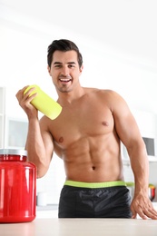 Photo of Young shirtless athletic man with protein shake powder in kitchen